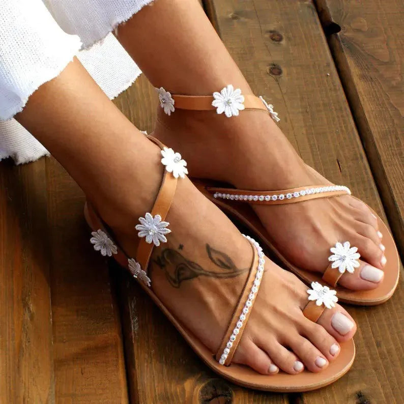 Brown ladies' Roman sandals with floral pattern and herringbone toe detail on a flat rubber sole.