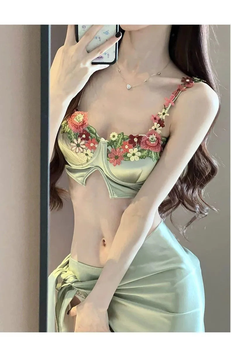 Green women's three-piece bikini set showing triangle top, briefs, and removable skirt laid flat.