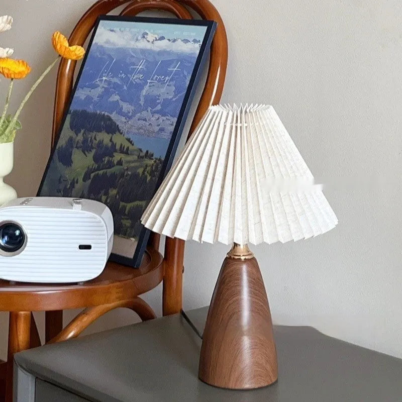 Tapered floral ceramic table lamp with remote control on a wooden surface.