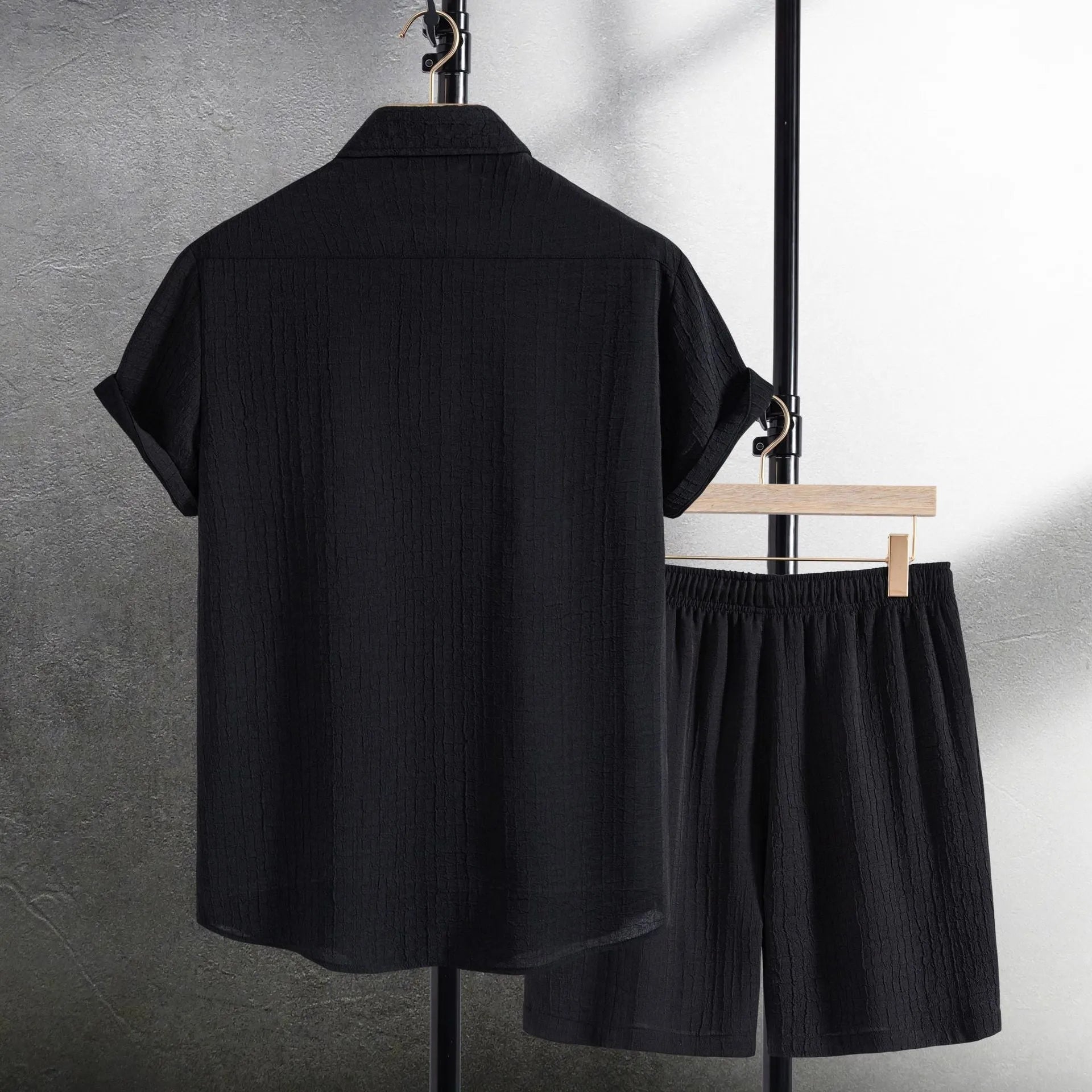 Men's black jacquard short sleeve shirt and shorts suit laid flat showing cotton blend fabric texture