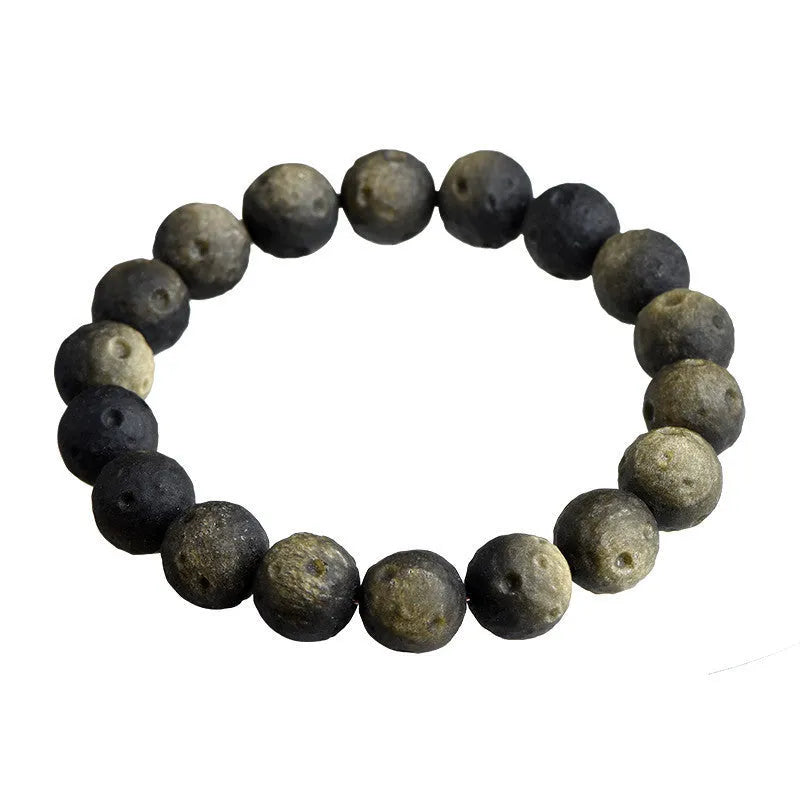 Natural obsidian crater ball bracelet with a ground texture in silver stone or gold colours on a wrist.