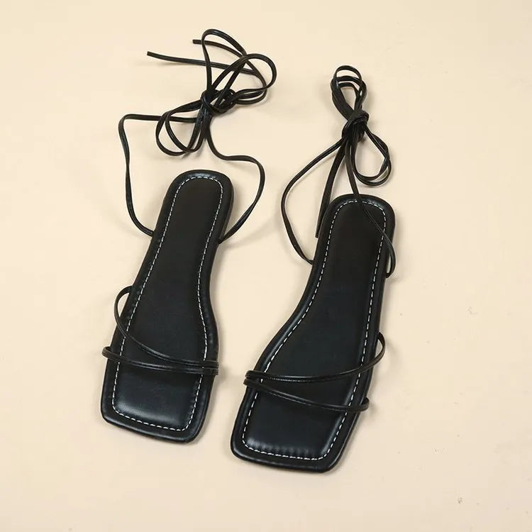 Women's flat sandals with ankle wrap strap and square toe in black, white, and orange colours.