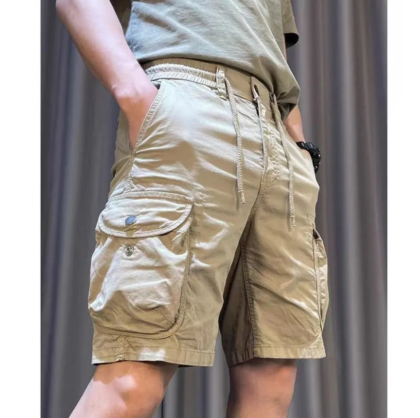 A pair of loose-fitting, straight-leg multi-pocket overalls trousers in a khaki colour on a model.
