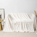 Thick coral fleece square blanket in a modern solid colour, draped over a sofa.