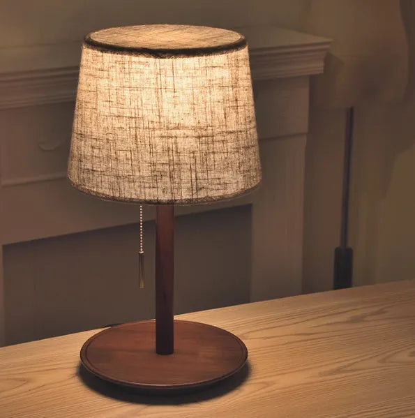 Walnut-coloured solid wood desk lamp with a white fabric lampshade and a black cord switch