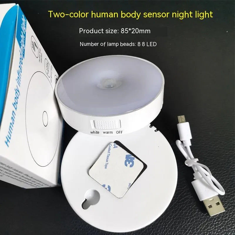 Small, round white LED night light with adhesive backing and a USB charging cable.