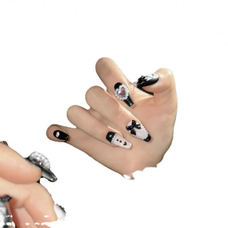 Black and pink heart pattern press-on nails with hand-painted bow decoration in cat's eye finish