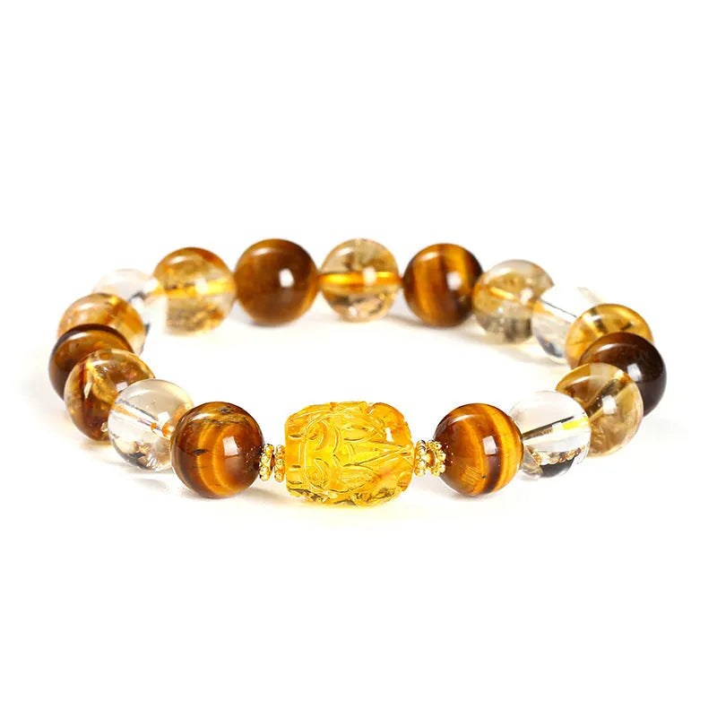 A close-up of a beaded bracelet with yellow banded Tiger's Eye and translucent citrine 10mm beads and a metallic Pi Xiu charm.