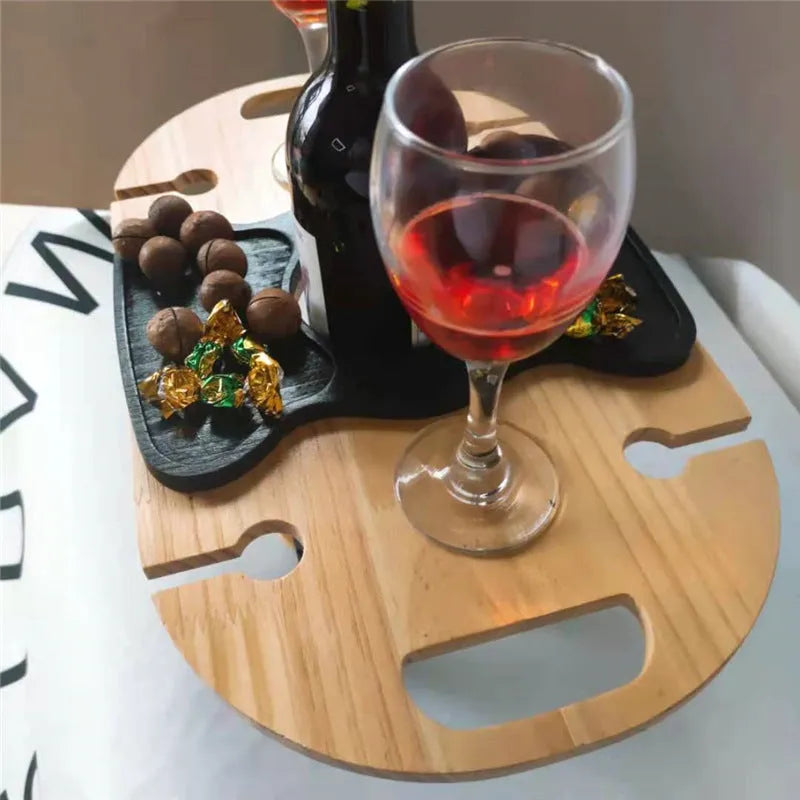 Creative multifunctional white wood wine glass rack tray with bottle holder handle holding four wine glasses and a bottle on a picnic table