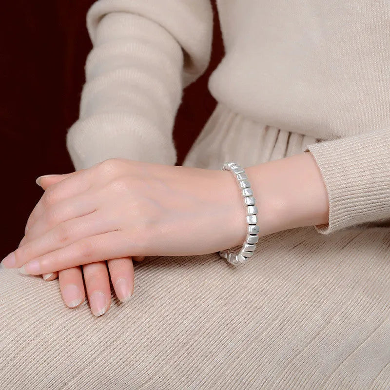 Women's handmade bracelet with irregular silver squares and wooden accents on elastic band