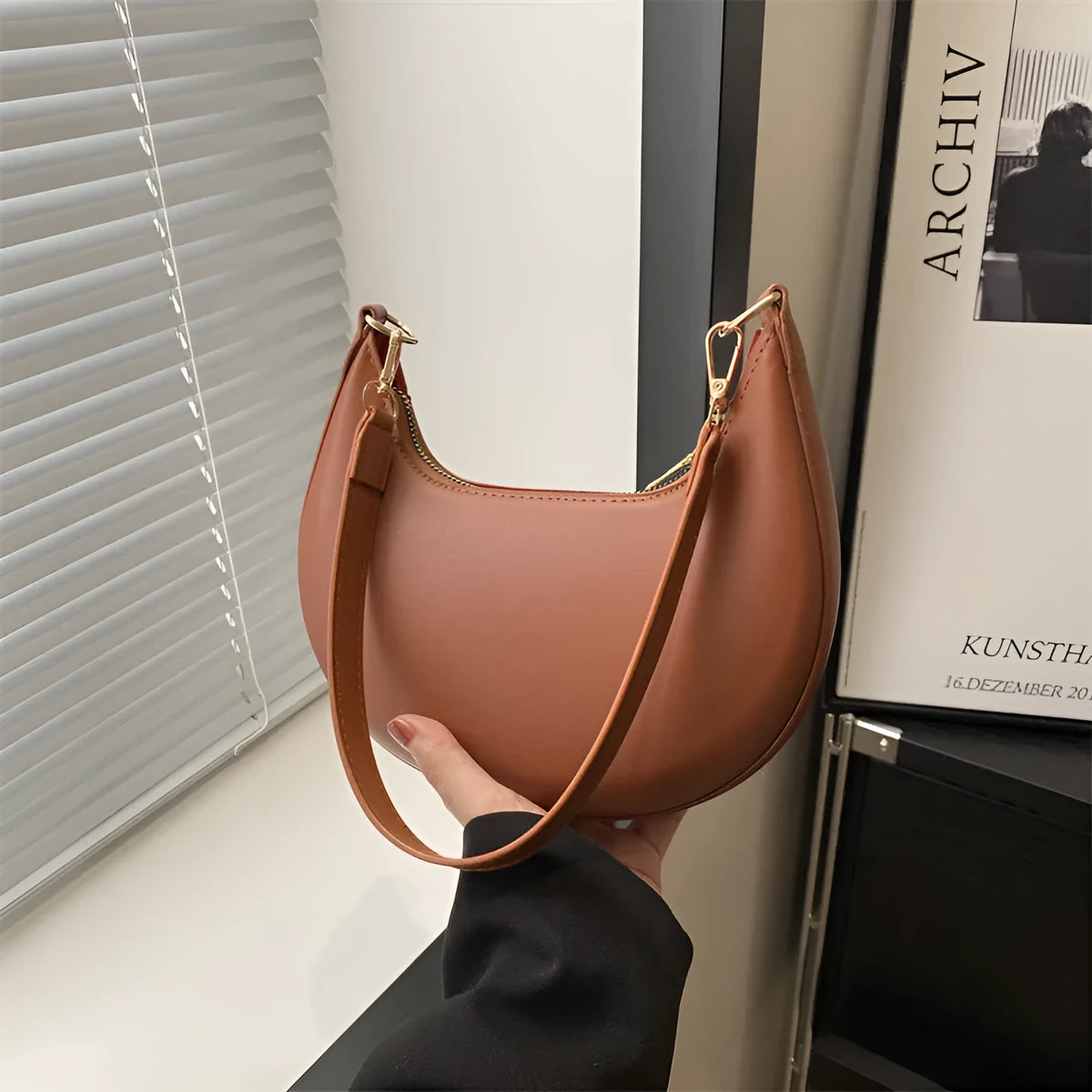 Round women's underarm bag in PU material showing sewing line detailing and internal phone compartment