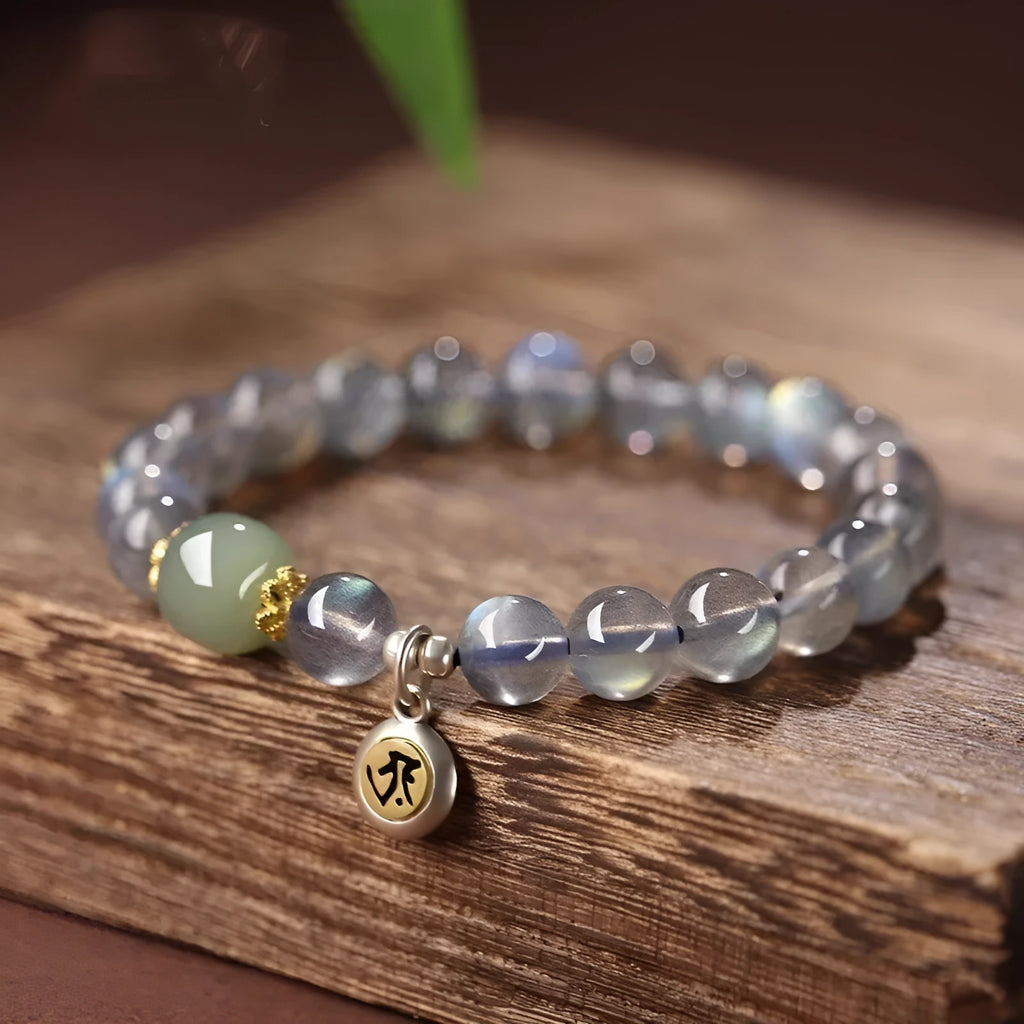 Close-up of an 8mm Moonstone crystal bracelet showing a detailed Thousand-Hand Kwan-yin mouse design.