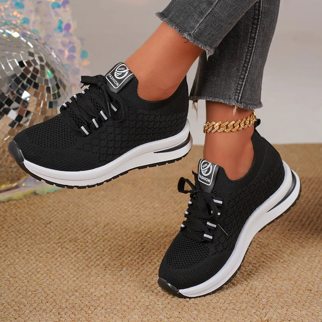 Women's black and white lace-up sneakers with mesh upper and flat rubber sole on a white background.