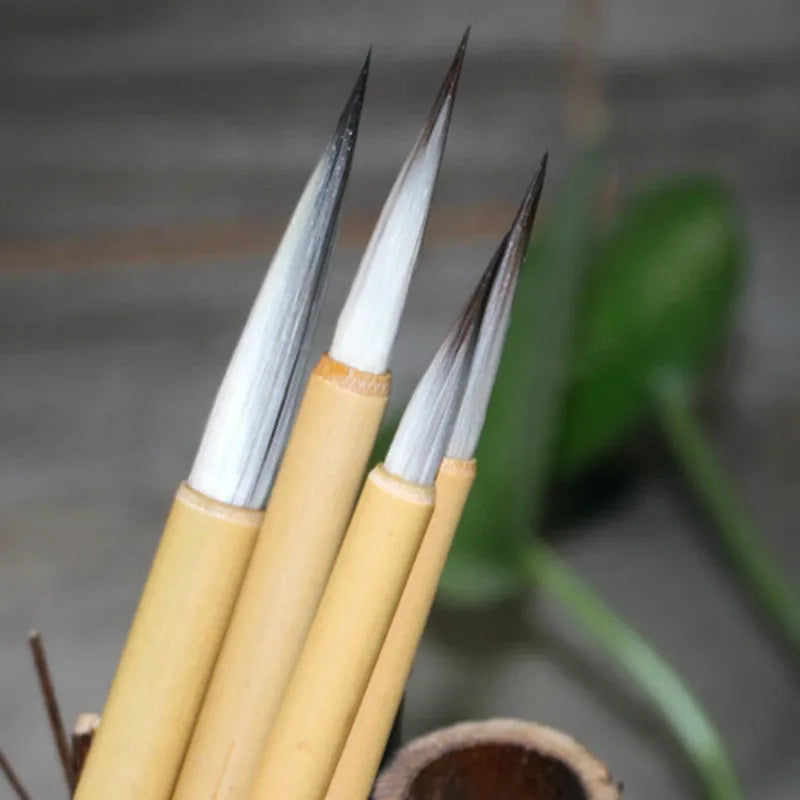 Set of four gold-coloured writing brushes with mixed hair bristles for calligraphy.
