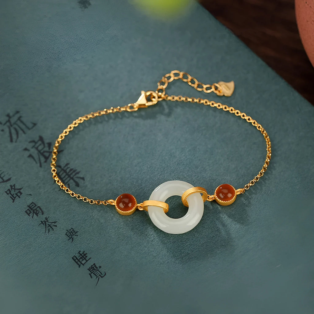Gold-coloured women's bracelet with a sterling silver base and an inlaid natural Hetian jade peace symbol buckle.