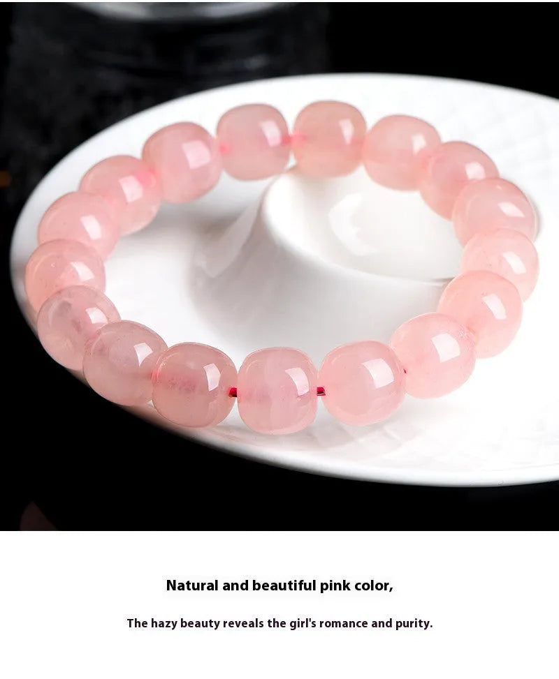 Pink natural crystal barrel bead bracelet with geometric beads on an elastic cord.