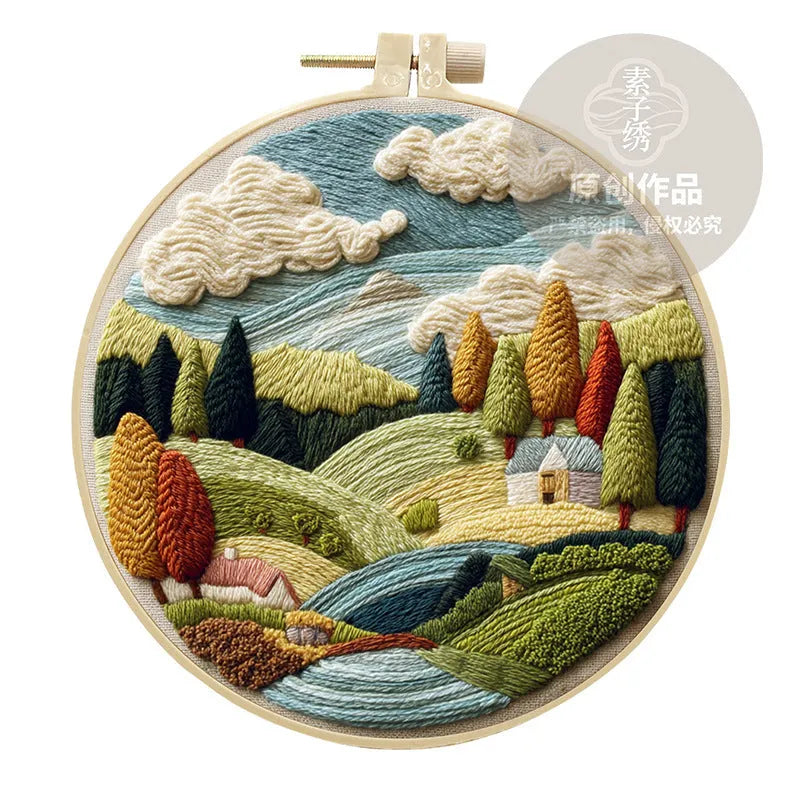 Complete DIY embroidery kit showing pre-printed landscape fabric, coloured threads, needles, and an embroidery frame.