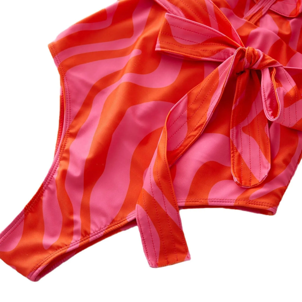 Women's printed one-piece swimsuit with ruffles on both shoulders and a deep V-neck with mesh stitching.