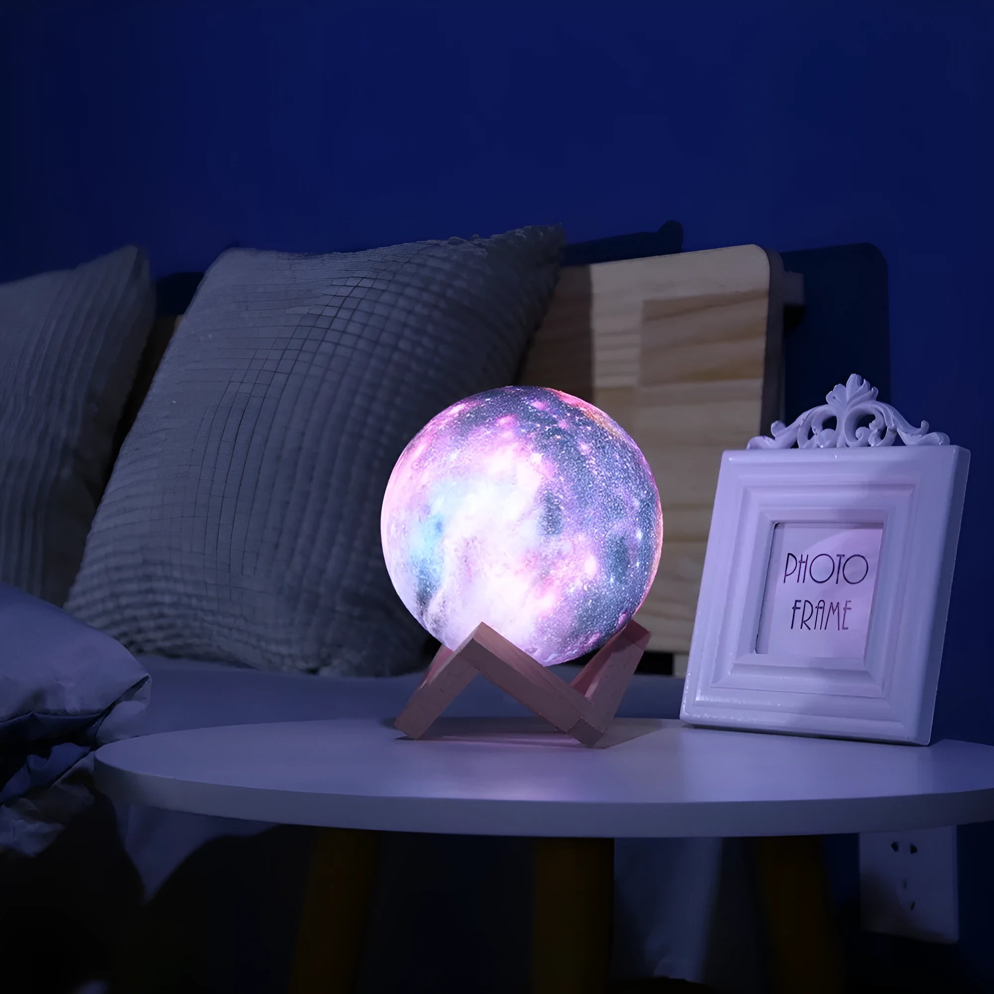 3D printed white lunar sphere night light glowing with soft yellow light on a dark surface.