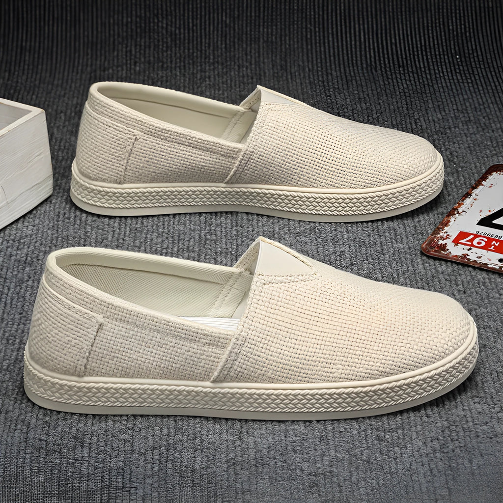 Men's beige linen canvas slip-on shoes with a round toe and shallow cut on a plain background.