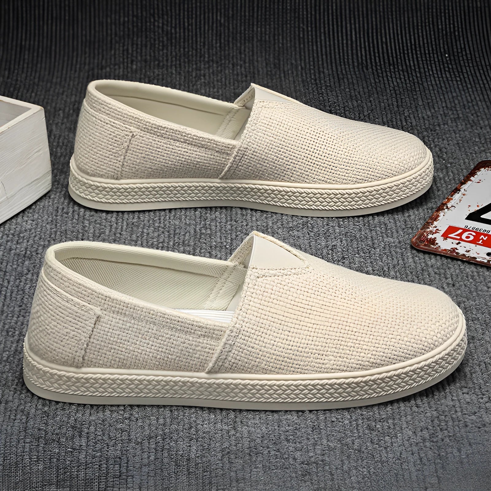 Men's beige linen canvas slip-on shoes with a round toe and shallow cut on a plain background.