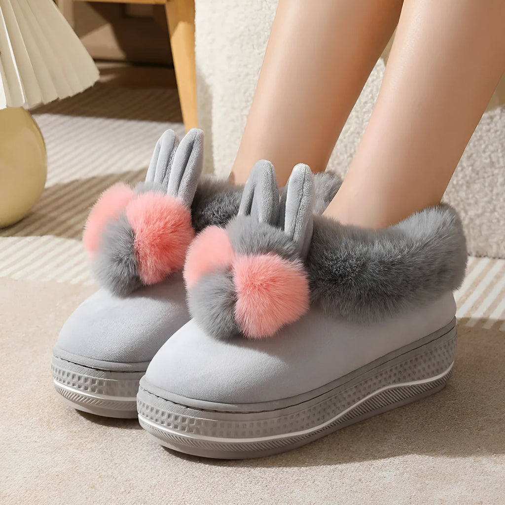 A pair of thick-soled grey plush oversleeve slippers with a textured non-slip sole.