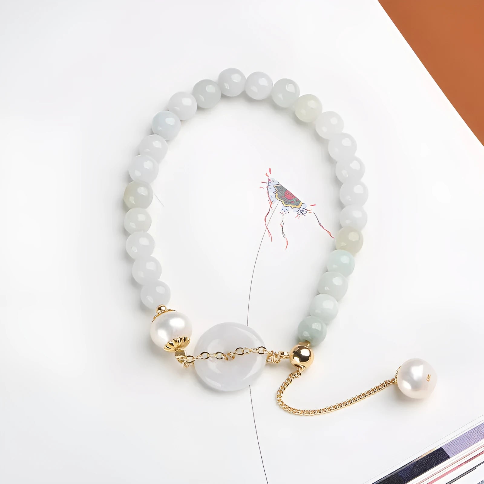 Jade and pearl bracelet with geometric pendant and peace buckle charm on wrist