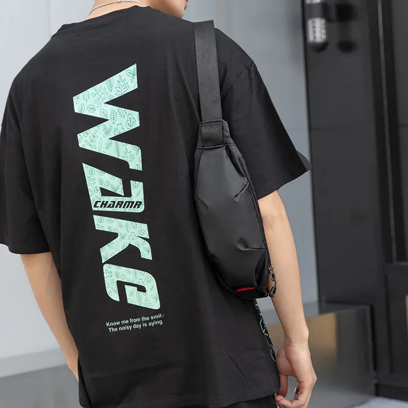 Black Oxford cloth waist pack for men worn crossbody, showing front zip and compact size.