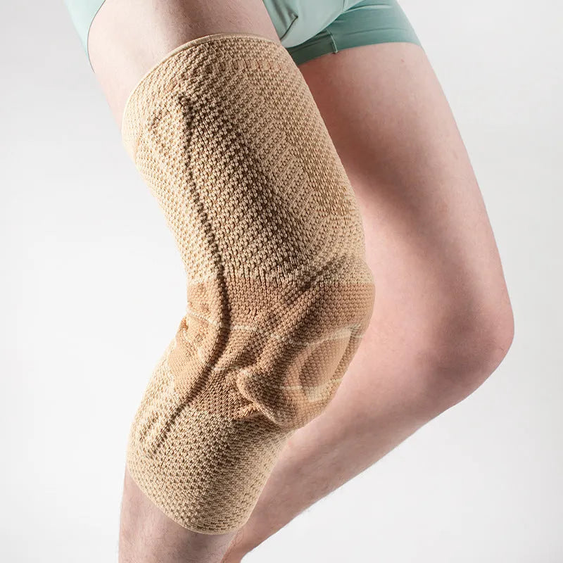 A pair of adult sports knee pads in a black and blue colourway, shown on a knee for scale.