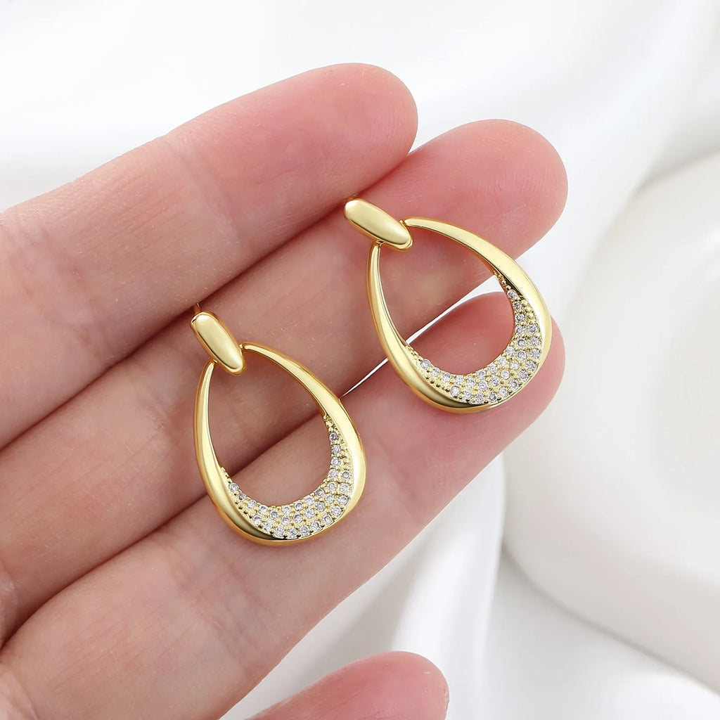 Yellow gold geometric drop-shaped women's earrings with round and oval ring elements on a simple background.