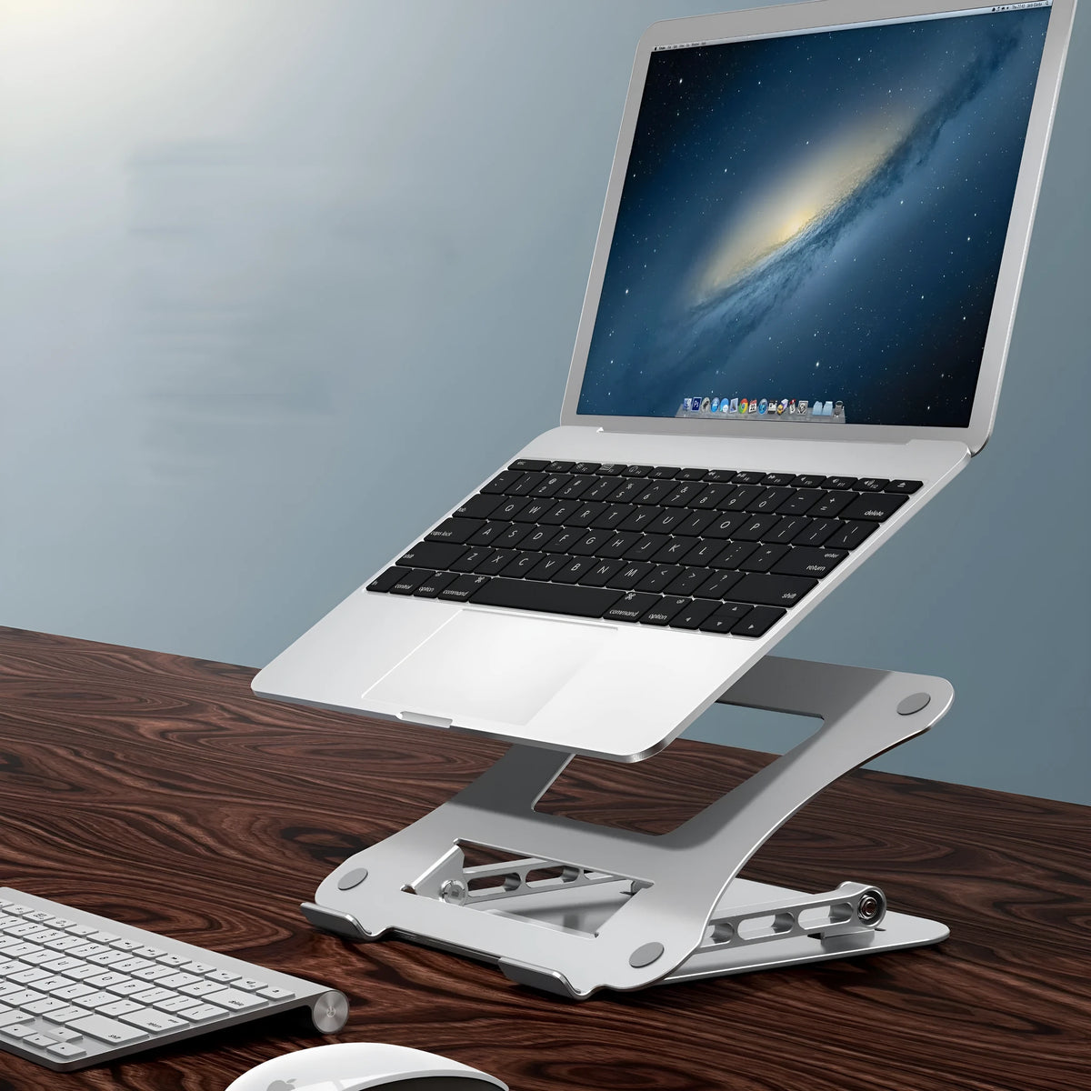 Silver aluminium alloy folding notebook cooling rack with open legs, next to a laptop on a desk