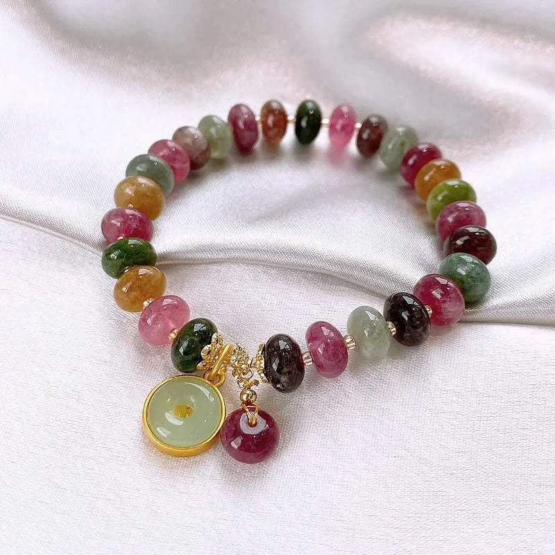 Colourful tourmaline beaded bracelet with geometric abacus beads and a rabbit pendant on a white background.