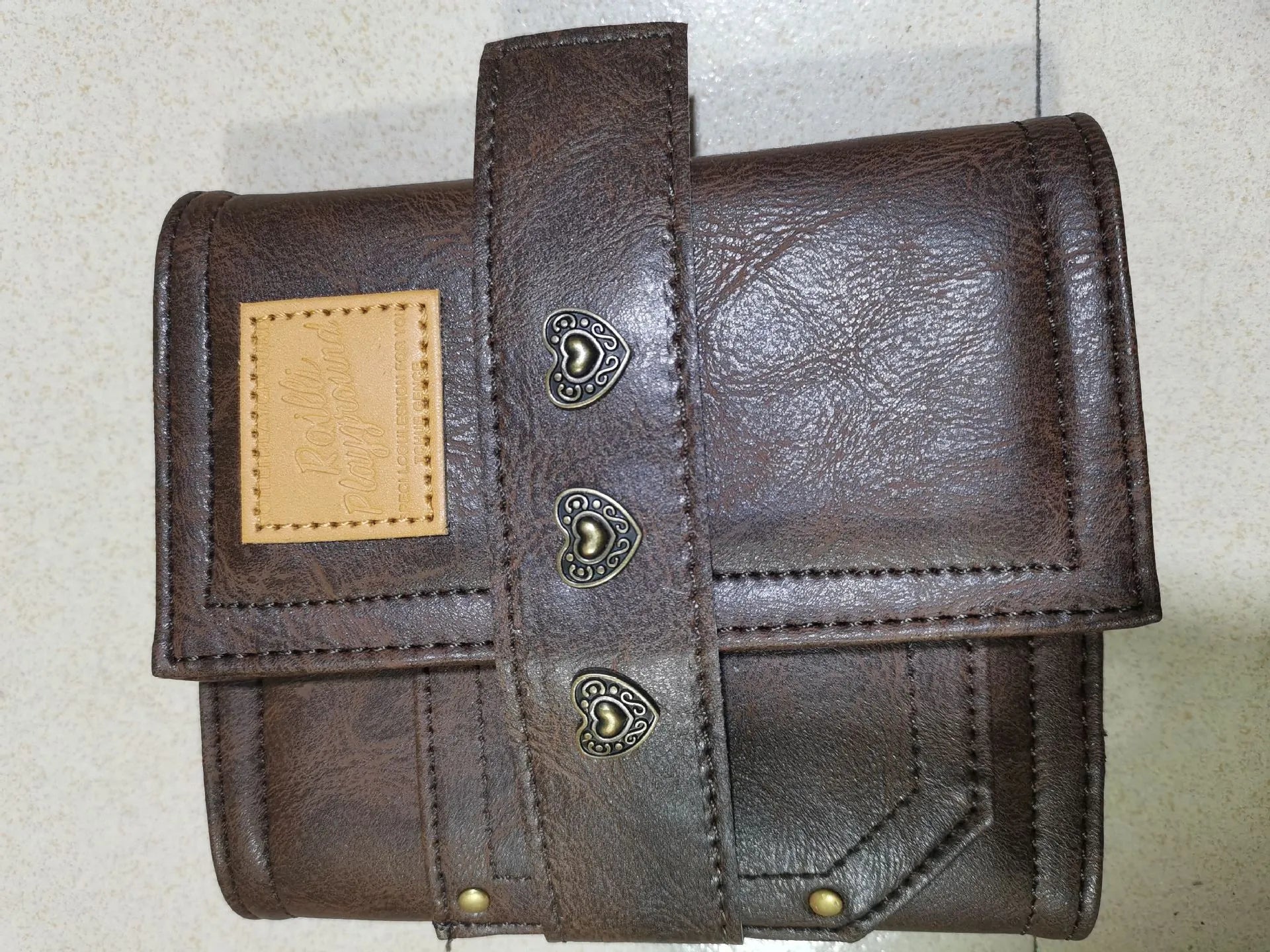Brown A7 notebook with a leather buckle closure on a PU cover, showing loose-leaf binding