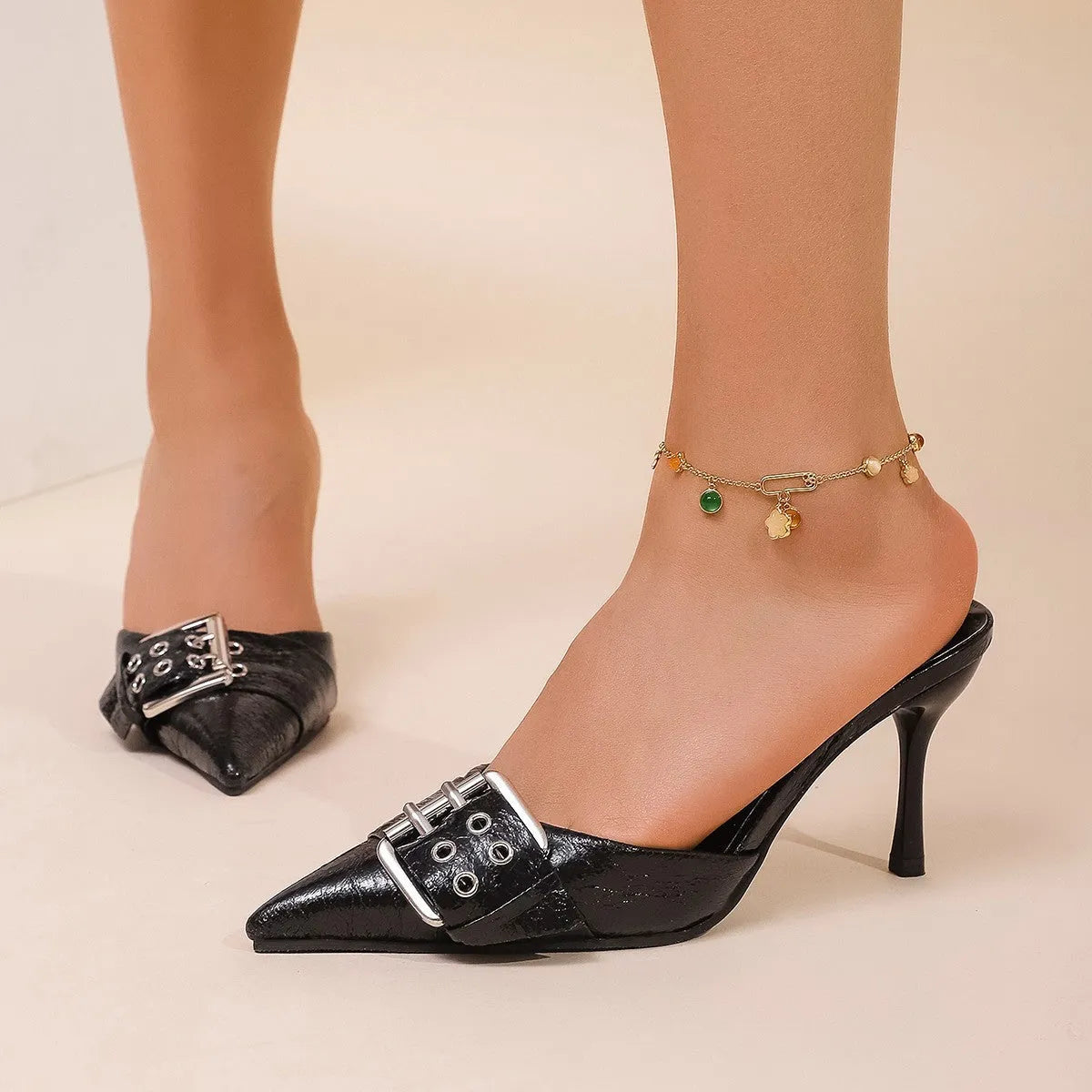 Black women's high heels with pointed toe and ankle strap featuring a decorative buckle.
