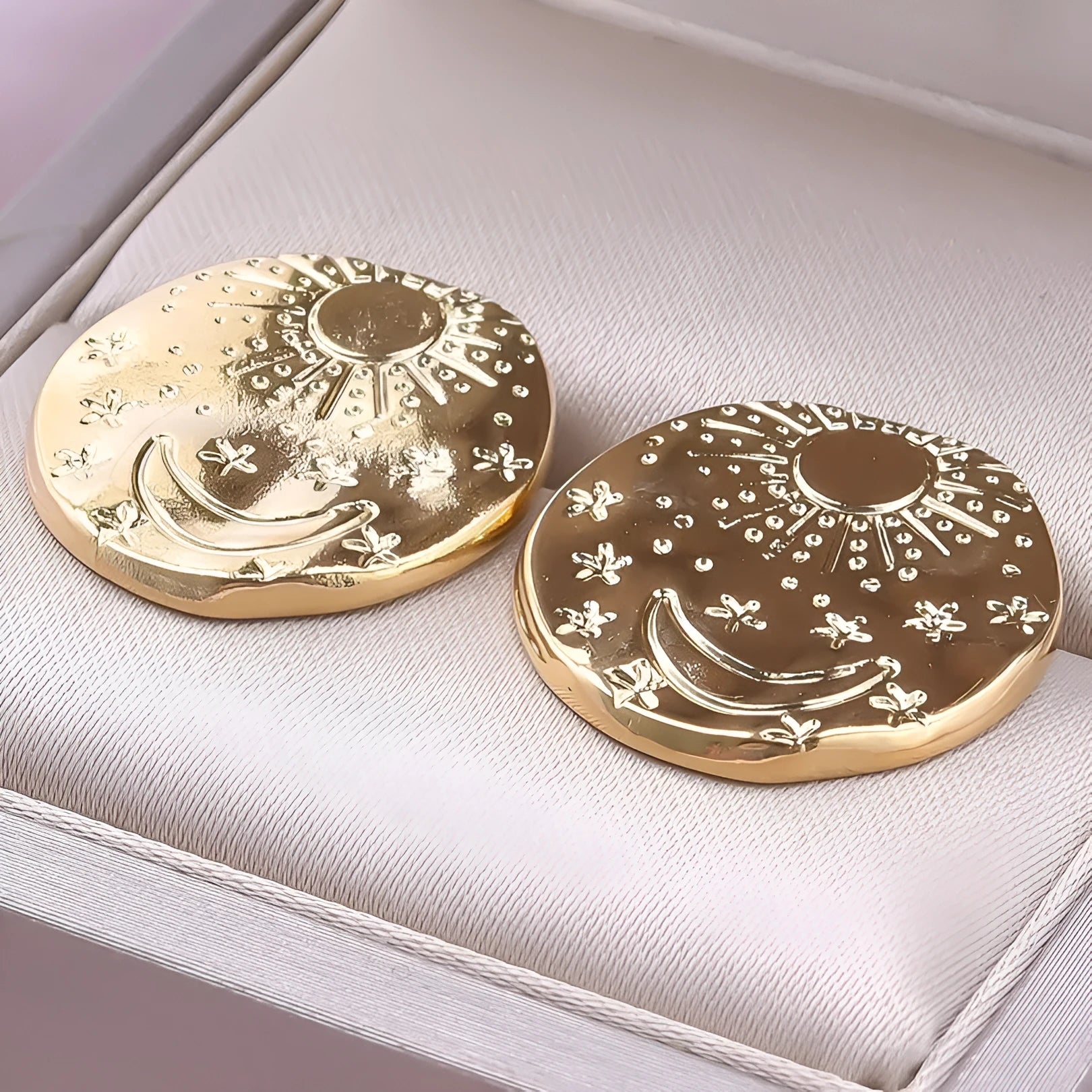A pair of geometric shell pattern stud earrings in a gold finish on a plain background.