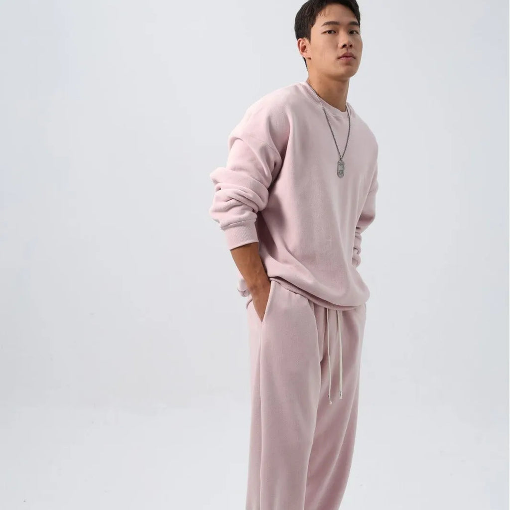 Men's black polar fleece sports suit with crew neck jacket and loose fit trousers laid flat.