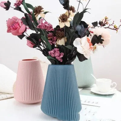 Colourful melamine plastic decorative flower vase on a desk, showing white, pink, green, and blue colour options.