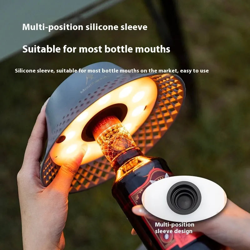 Beige wine bottle shaped camping lantern with USB-C port on a wooden table.