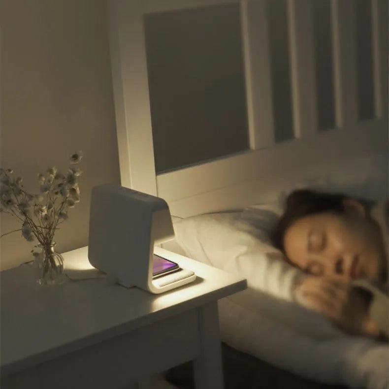 White 3-in-1 bedside lamp with wireless charging pad, LCD alarm clock screen, and touch-sensitive dimming control.