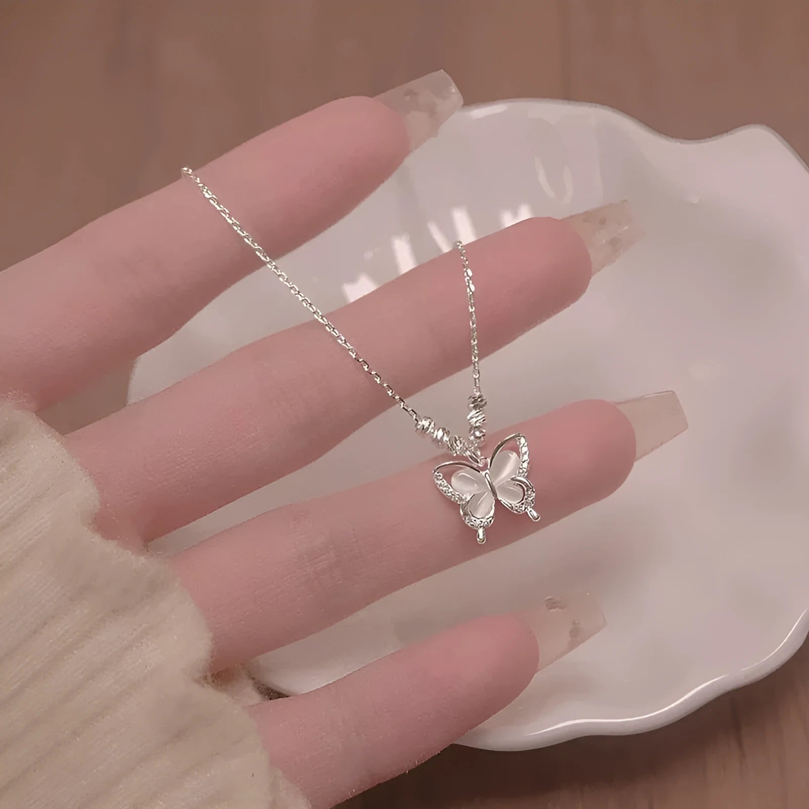 Silver necklace with a square opal butterfly pendant on a cross chain, shown against a white background.