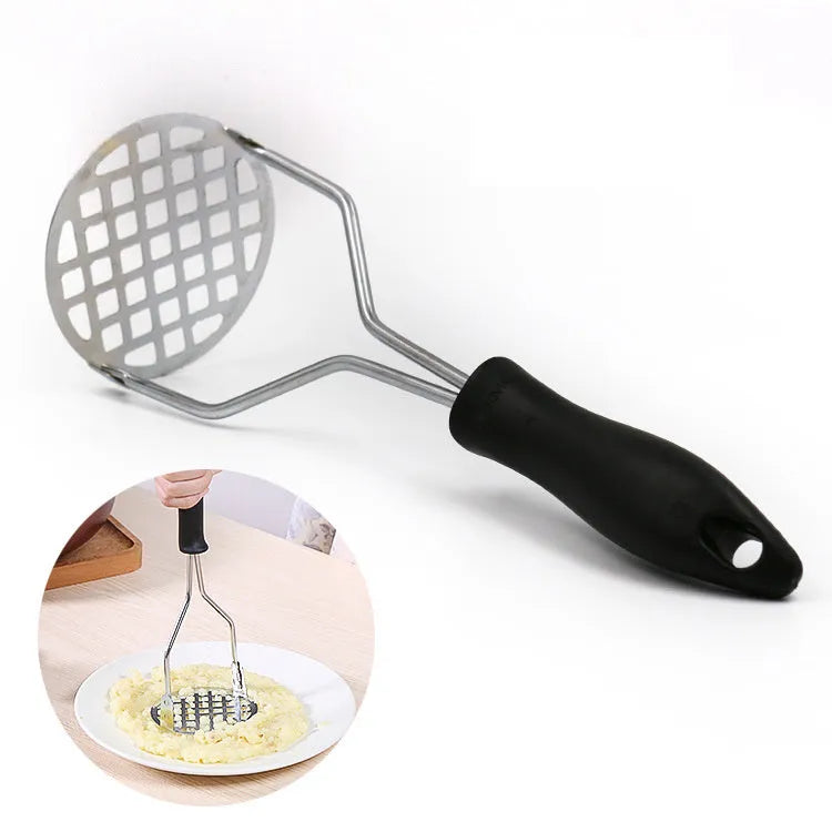 Manual potato masher with wooden handle and flower-shaped iron plated press head on a light surface
