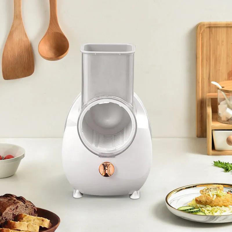 White electric vegetable slicer with rotary grater, feeding port, and three cutting blade pairs on kitchen counter