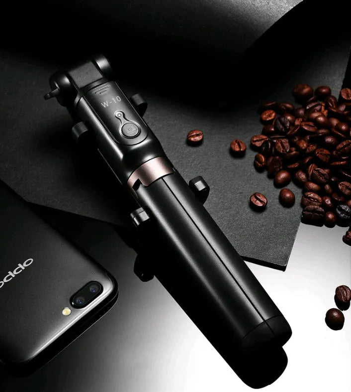 Aluminium telescopic Bluetooth selfie stick with tripod base and remote control next to a smartphone.