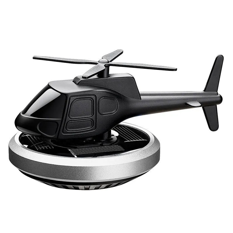 Silver metal solar helicopter car perfume ornament rotating on a car dashboard.