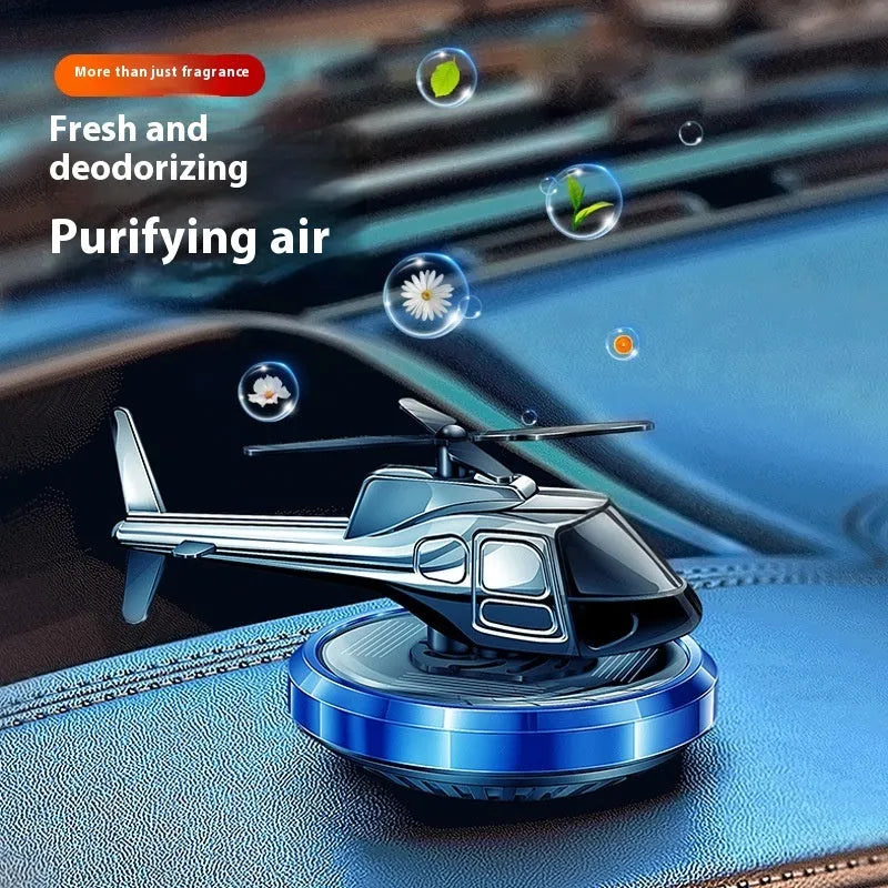 Silver metal solar helicopter car perfume ornament rotating on a car dashboard.