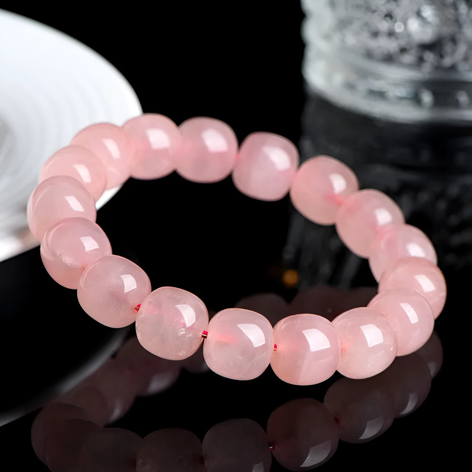 Pink natural crystal barrel bead bracelet with geometric beads on an elastic cord.