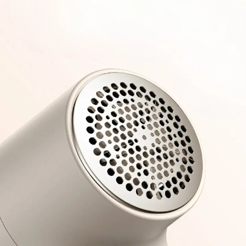 White electric lint remover with LED display and USB port on a fabric background.