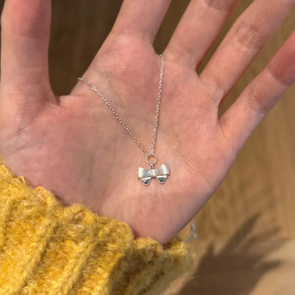 925 silver matte bow necklace with electroplated gold finish on display
