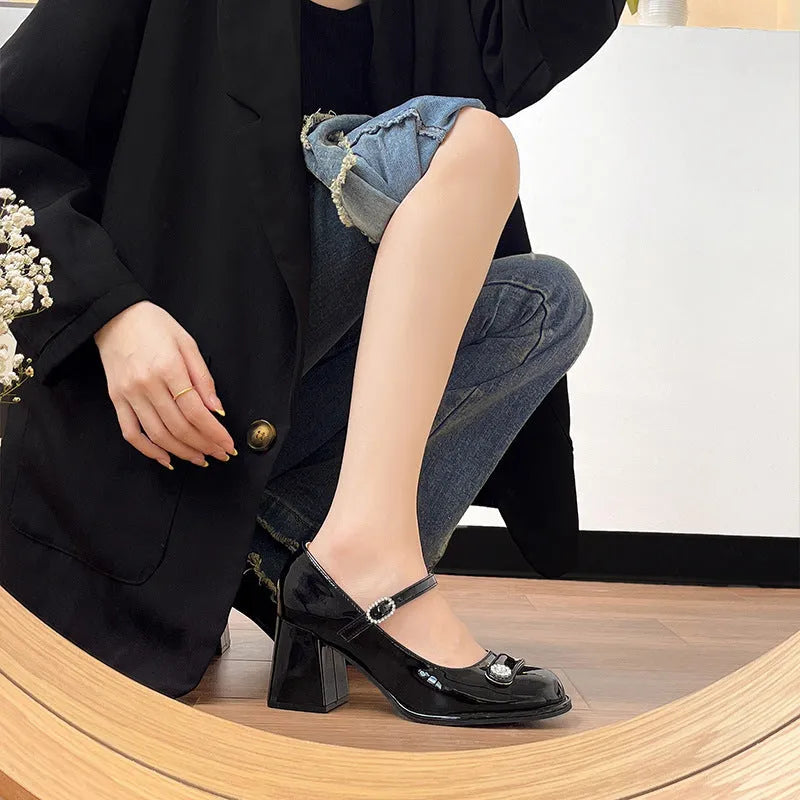Women's black patent leather chunky heel court shoe with round toe and buckle fastening.