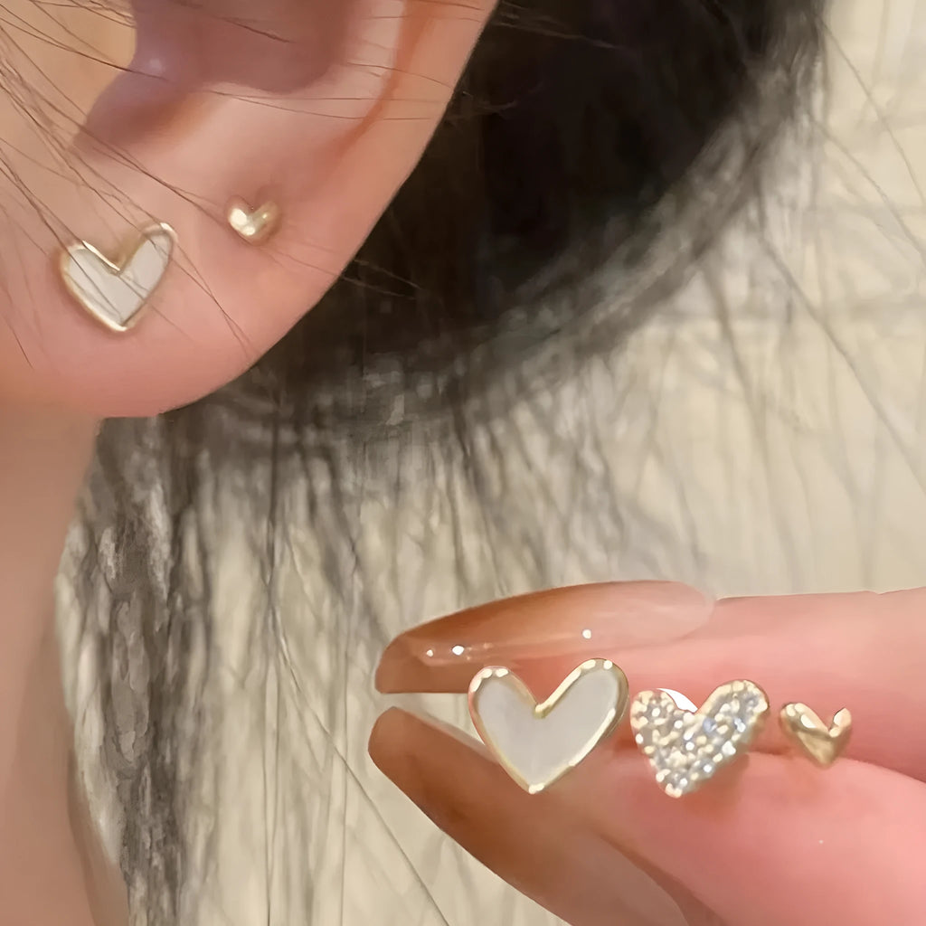 Three pairs of women's alloy heart-shaped earrings in gold, black, black-white, and pink colours
